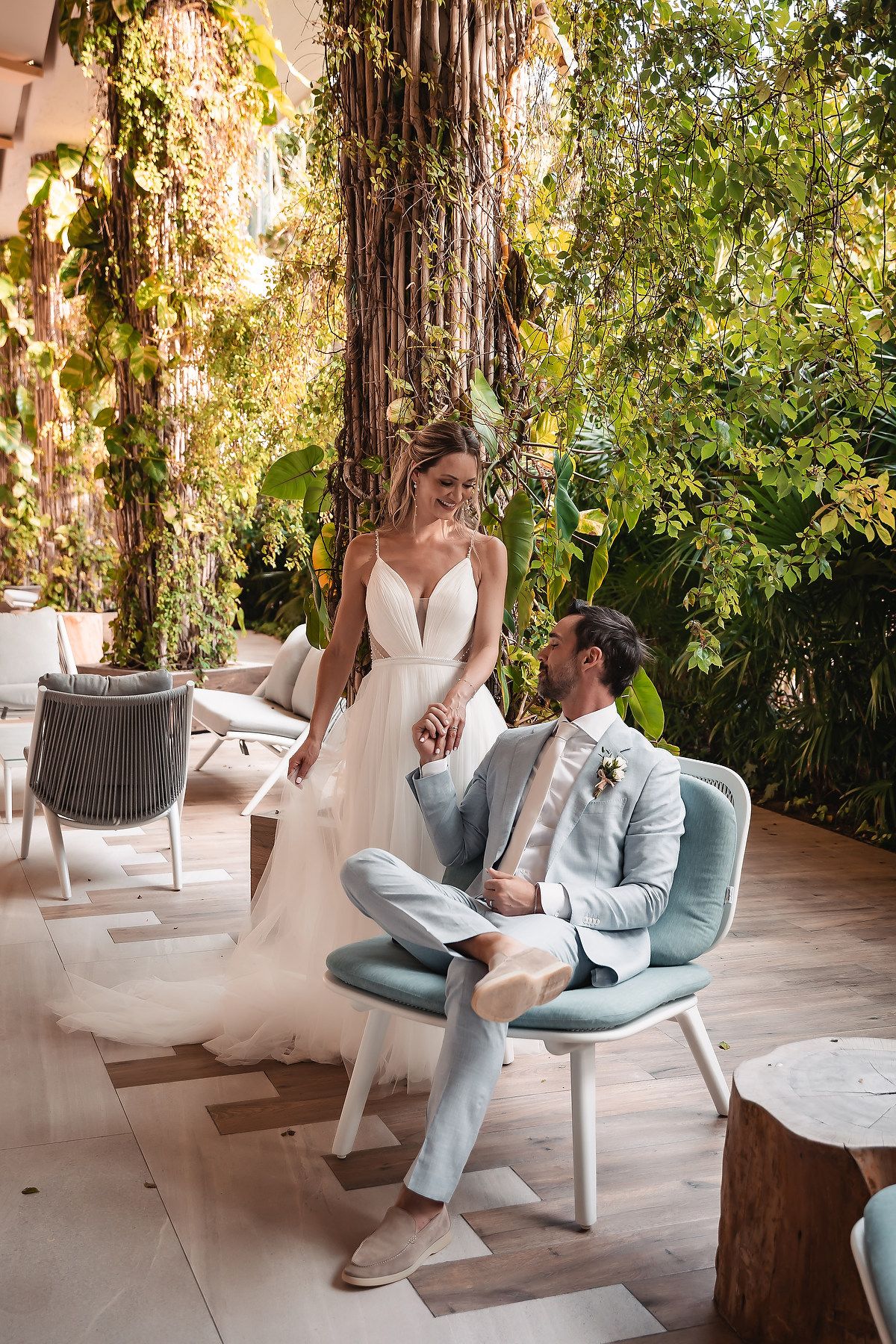 A couple interacts on sleek modern furniture in a tropical garden setting.
