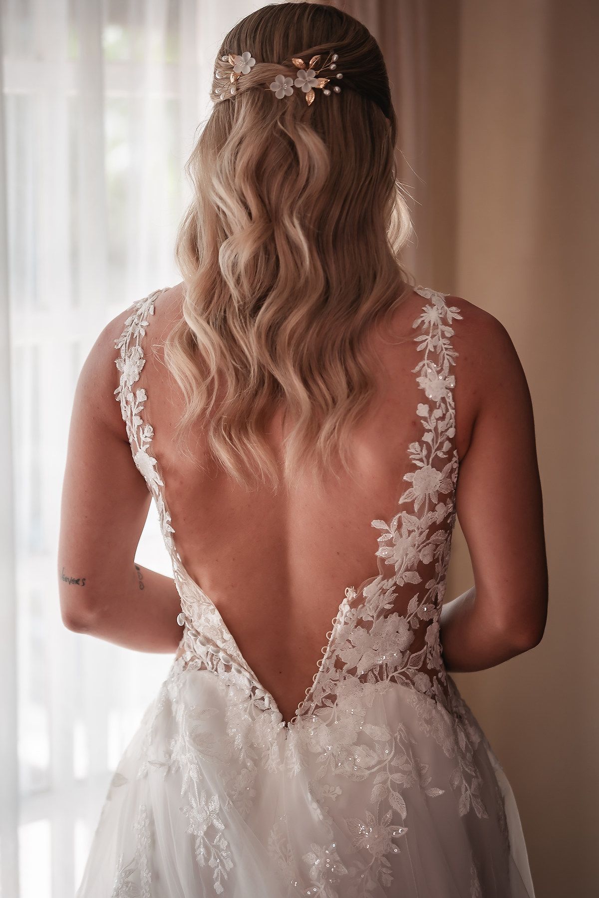 Back view of a wedding dress showing intricate lace details and deep V-cut design.