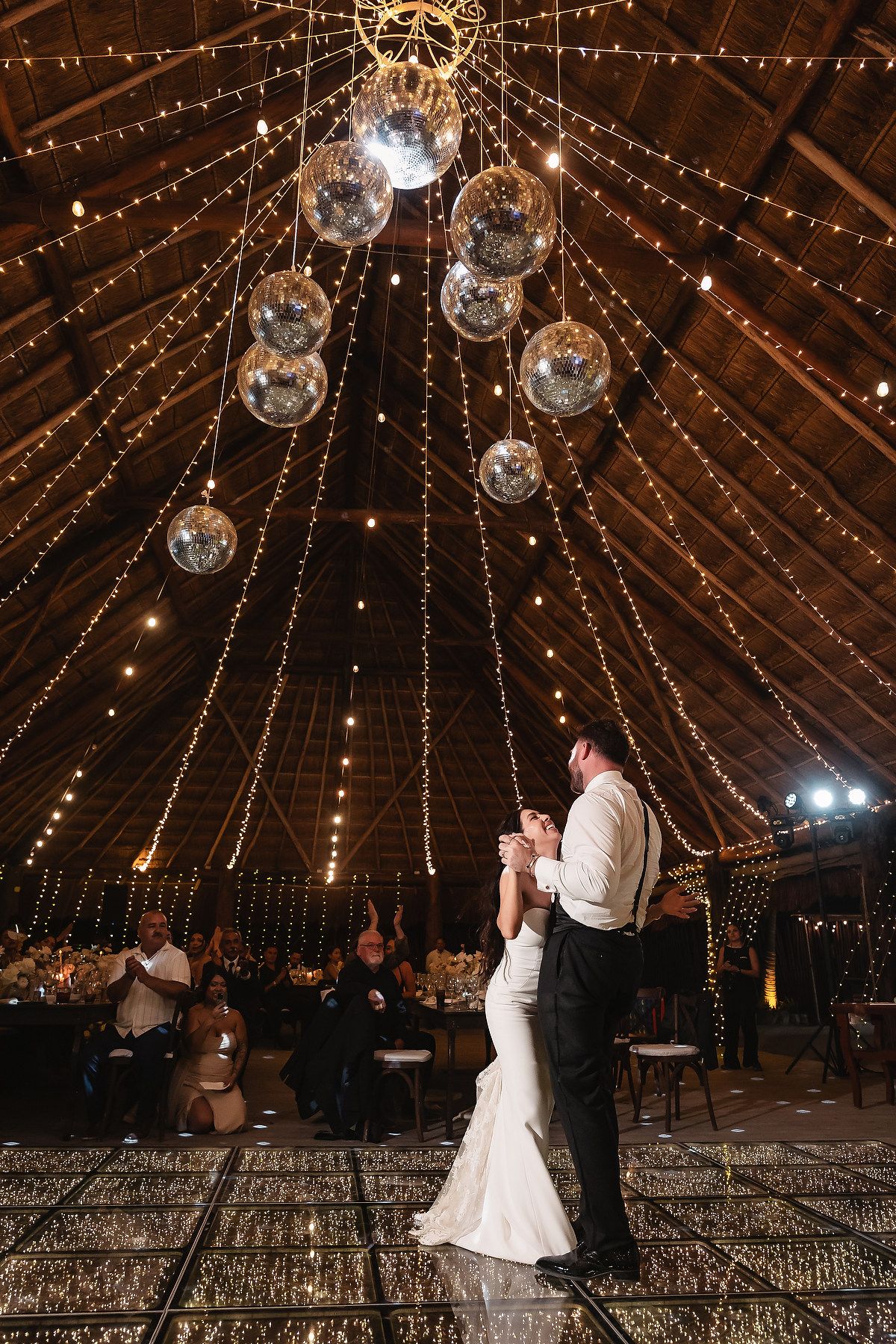 A romantic wedding dance captured under sparkling lights and disco balls in a rustic venue.