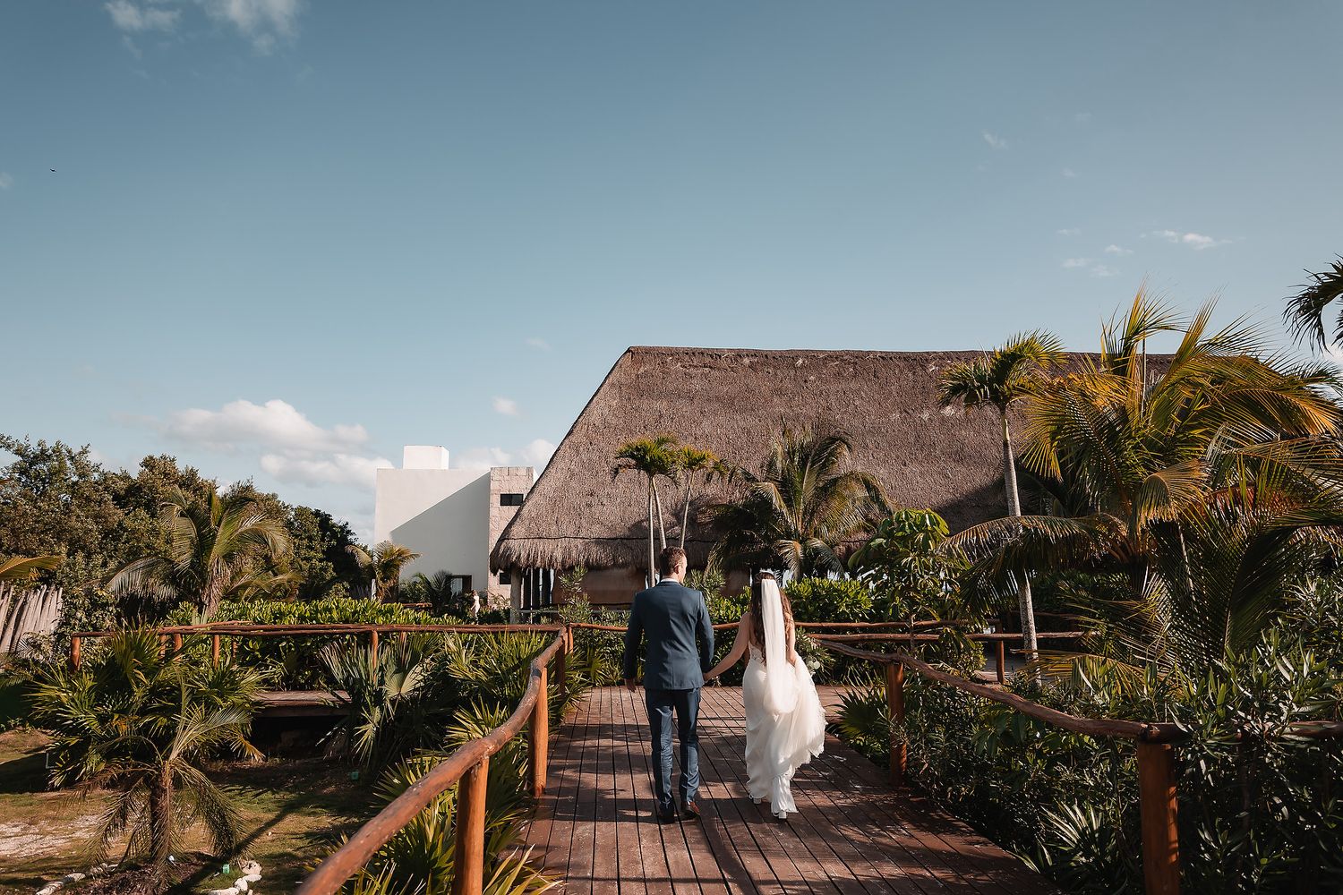 Panoramic view of a tropical beach venue with thatched roof structures and palm trees.