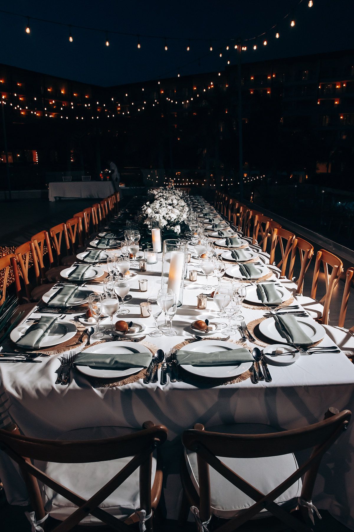 Elegant wedding reception table setting with string lights and white linens.