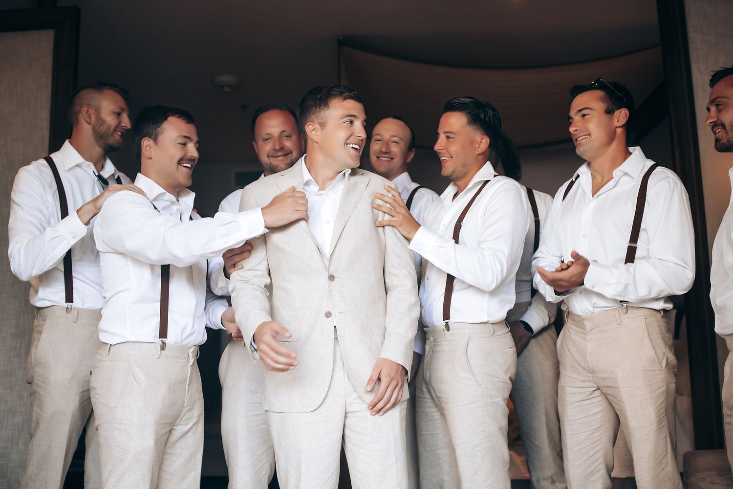 Group wearing matching white shirts and light colored suits standing together in celebration.