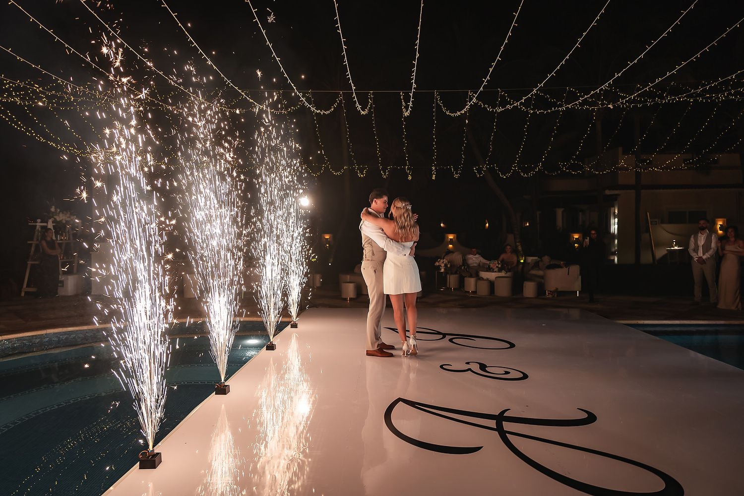 Wedding celebration with dramatic sparkler fountains on dance floor at night.