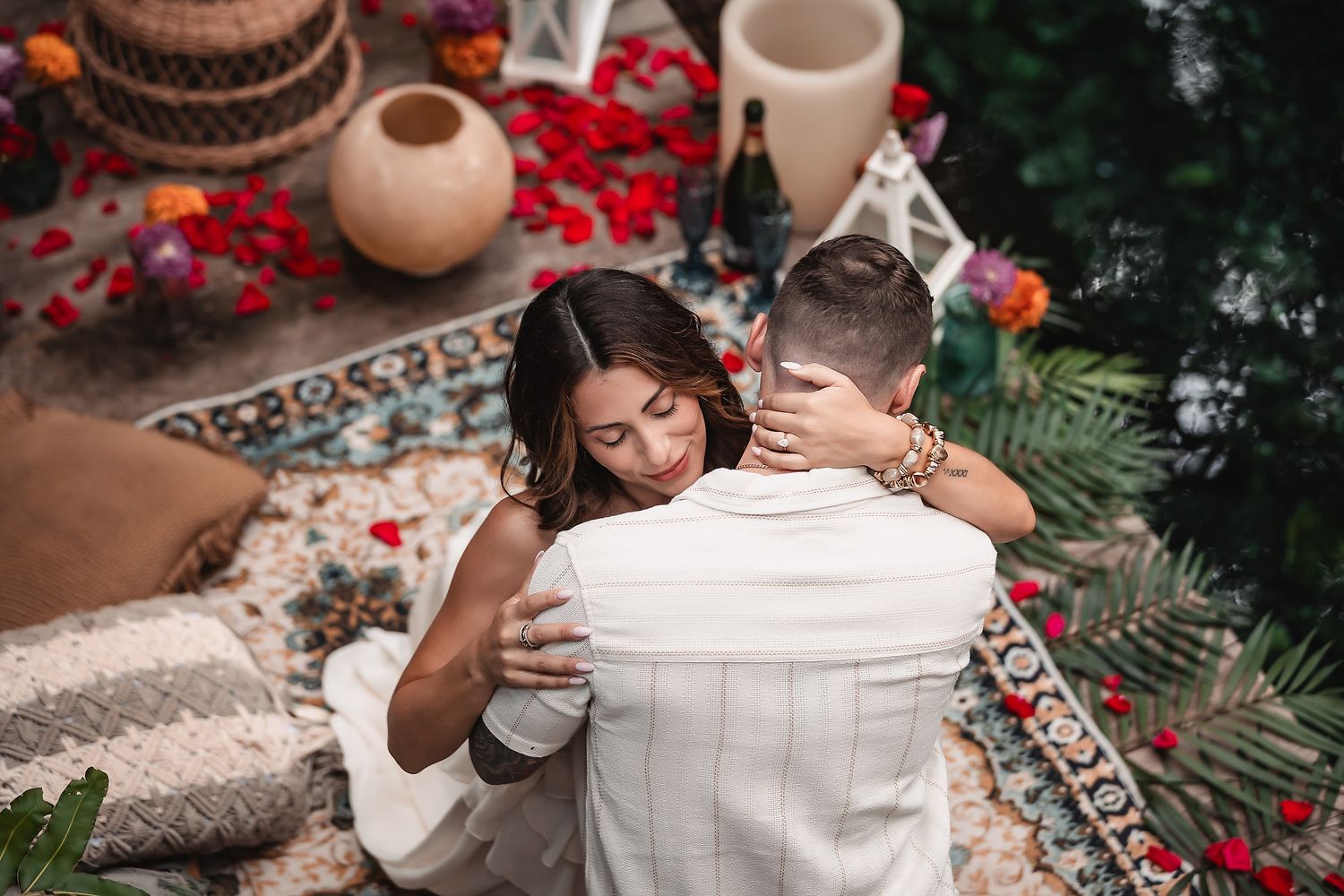 Intimate moment captured on decorative blankets with palm fronds and lanterns.