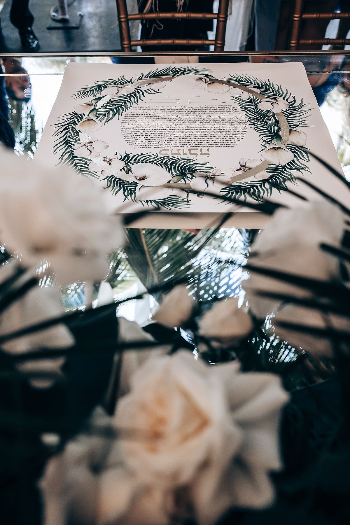 Wedding invitation card decorated with delicate greenery and ferns in a circular wreath pattern.