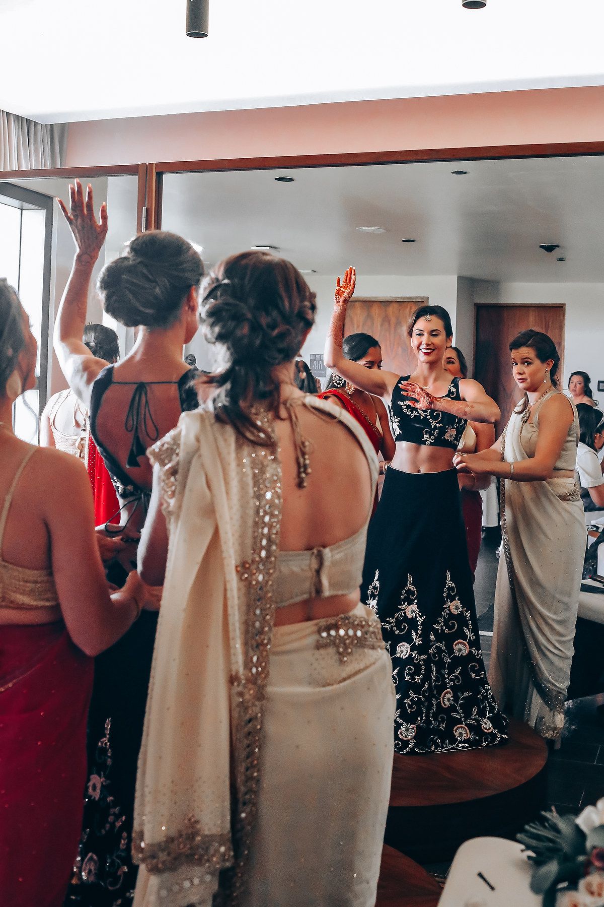Wedding guests dance and raise their hands in celebration during a reception party in an indoor venue.