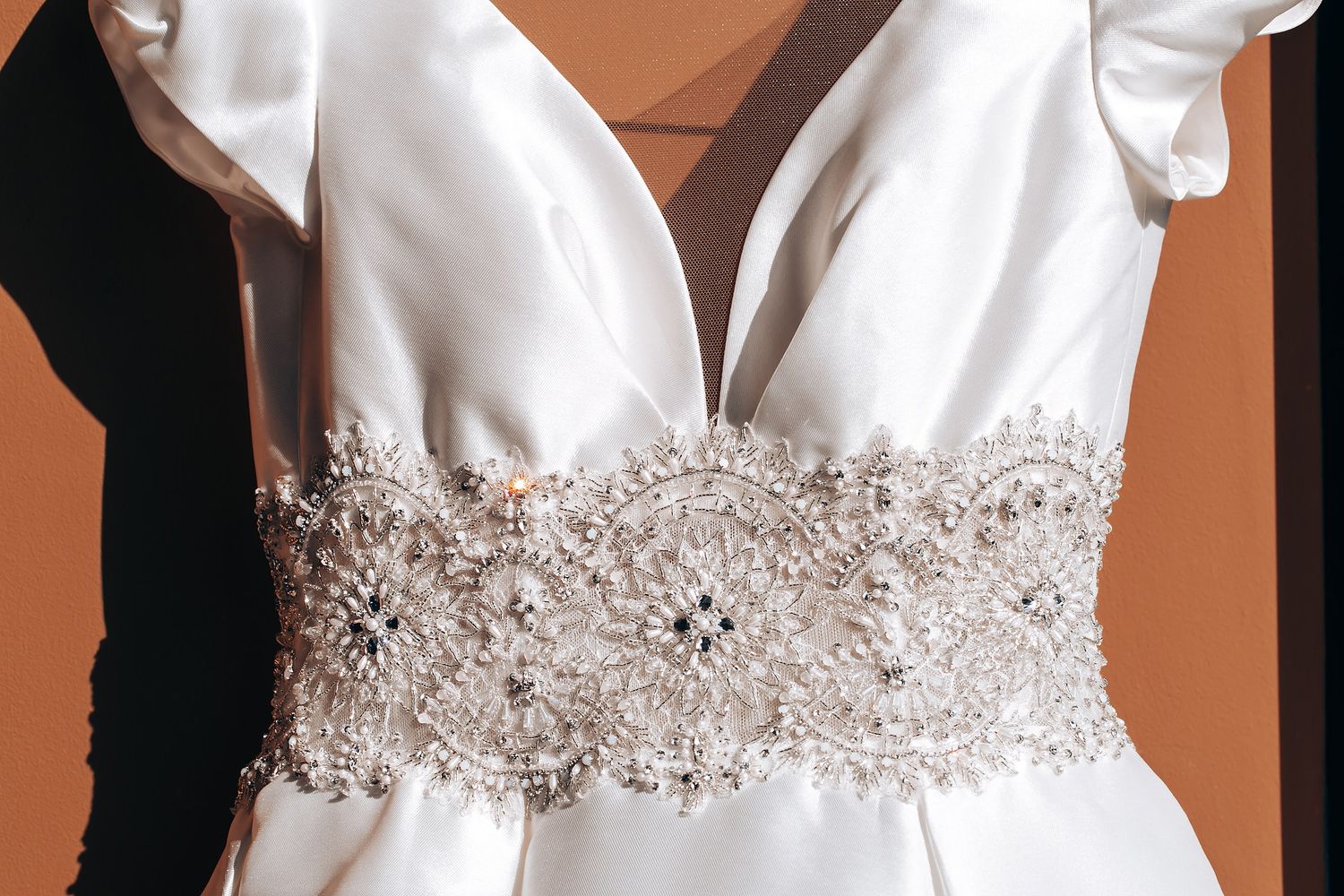 Close-up detail of white wedding dress bodices showing beaded embellishments and lace trim details.