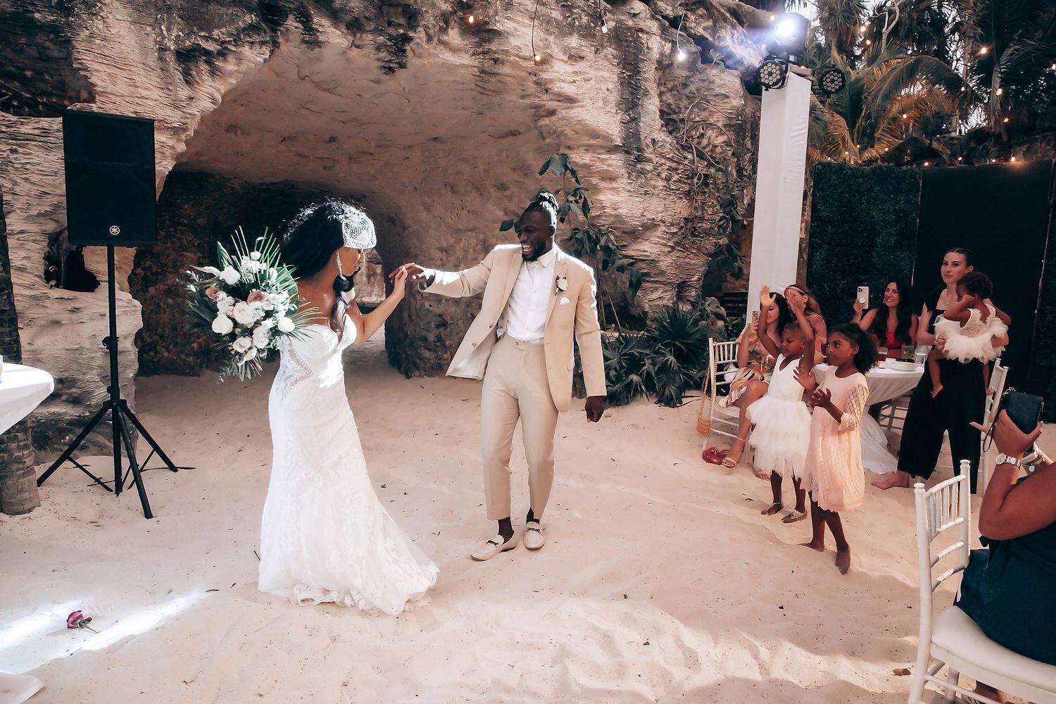 Wedding celebration in a rustic beach cave setting with natural stone walls.