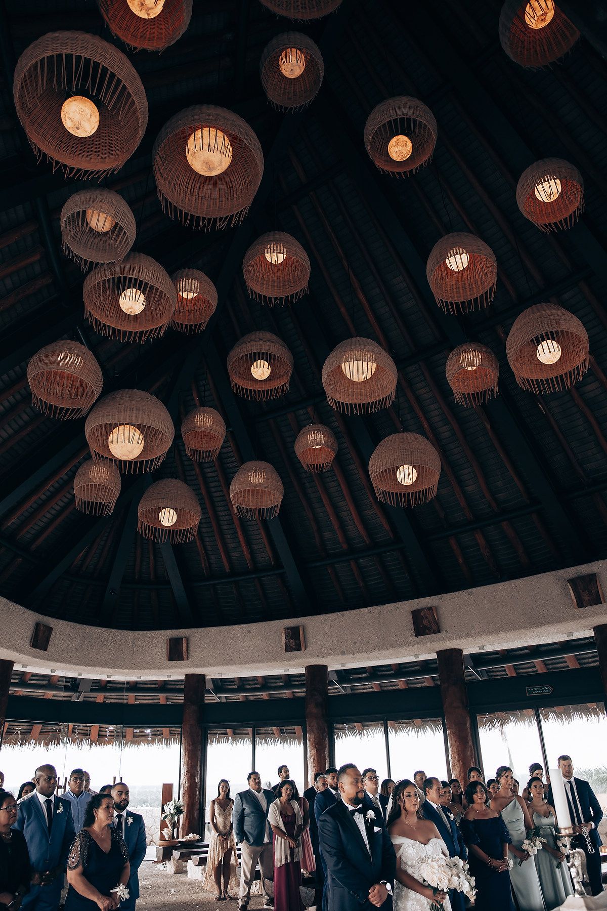 Dramatic circular pendant lights illuminate gathering space with high domed ceiling.
