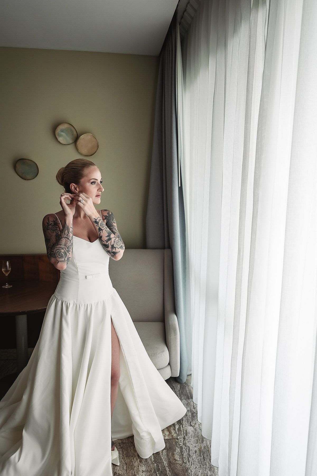 Elegant white wedding dress with flowing sleeves photographed near window light.