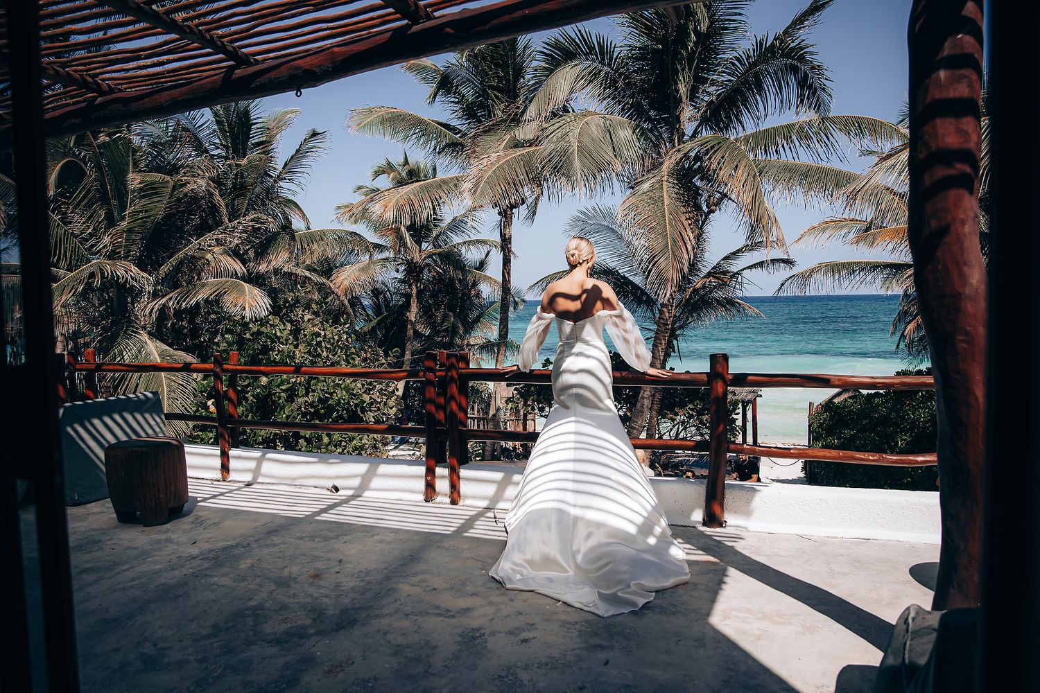 Beachside wedding celebration on a covered terrace with palm trees and ocean views.