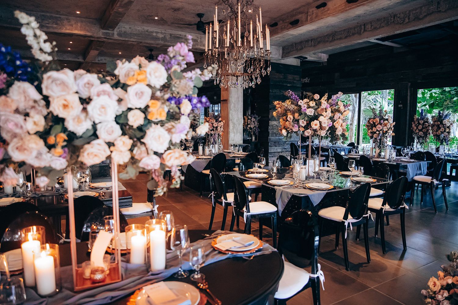 Elegant wedding reception venue with floral centerpieces, chandeliers, and candlelight creating a romantic atmosphere.