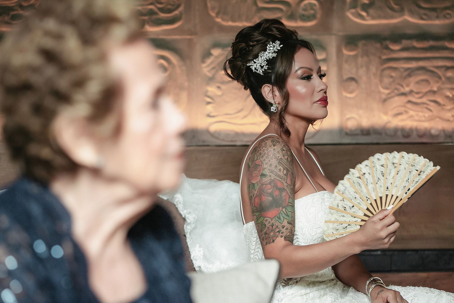 Elegant bride in a white lace gown poses against an ornate copper-toned wall in a romantic setting.