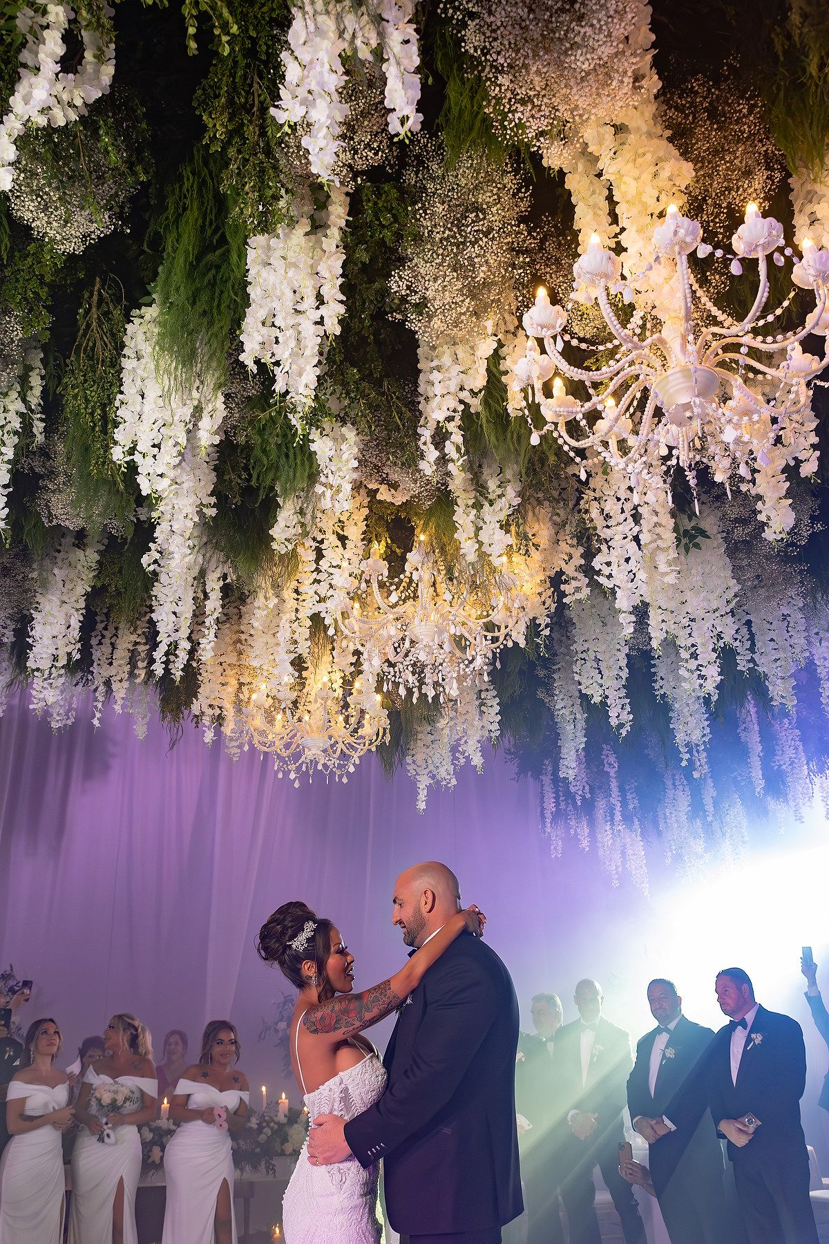 Newlyweds share their first dance under a stunning ceiling of cascading white wisteria and crystal chandeliers.