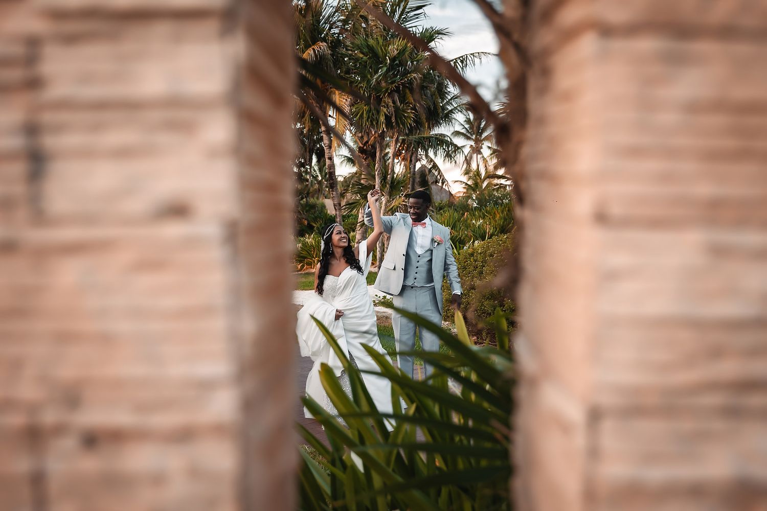 A creative wedding photo captured through architectural elements with palm trees in the background.