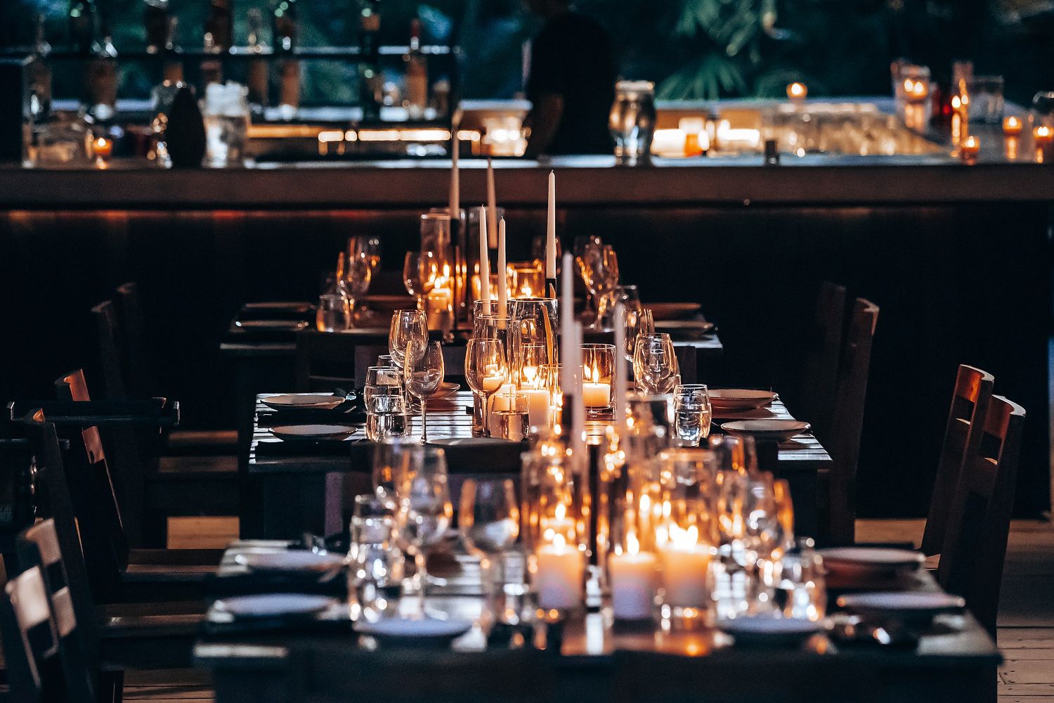 Candlelit wedding reception tables set with elegant glassware and place settings.