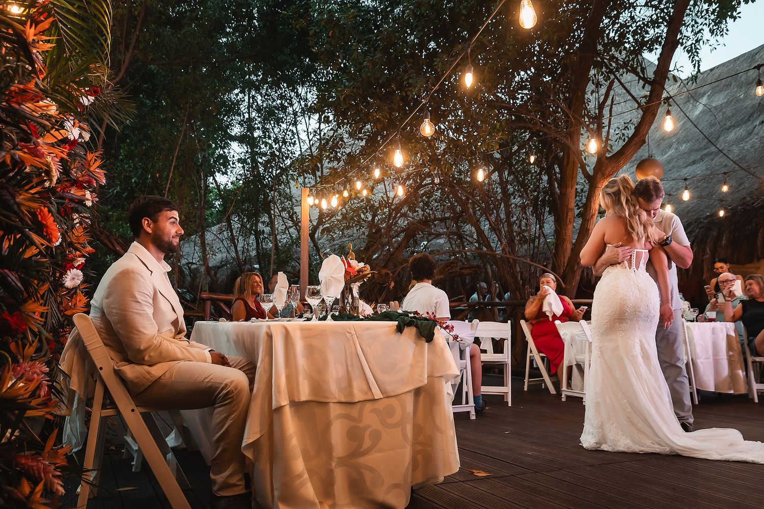 Evening outdoor reception with couple dancing while guests dine at decorated tables.