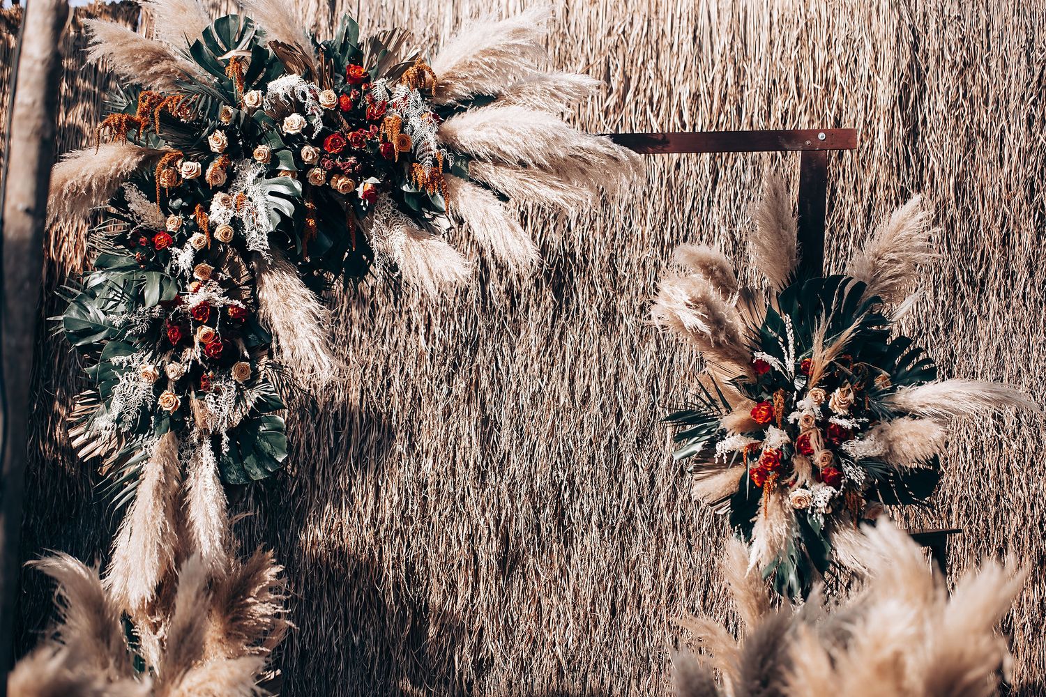 Rustic outdoor wedding venue with dried floral arrangements and thatched roof details.