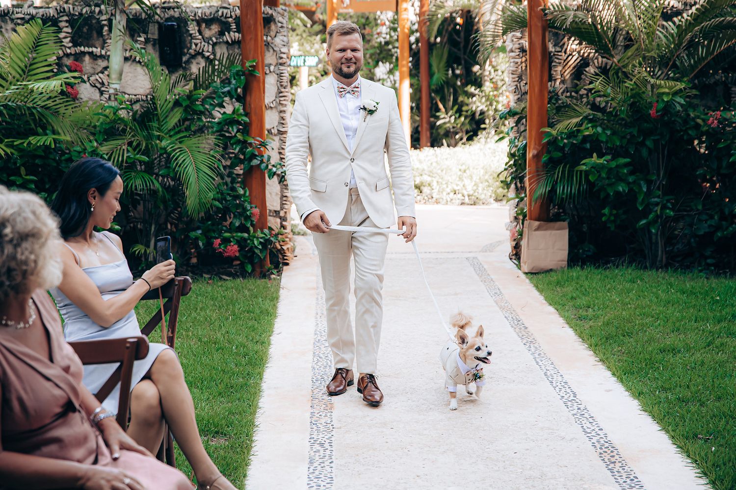 Outdoor wedding ceremony setup with tropical garden backdrop and floral decorations.