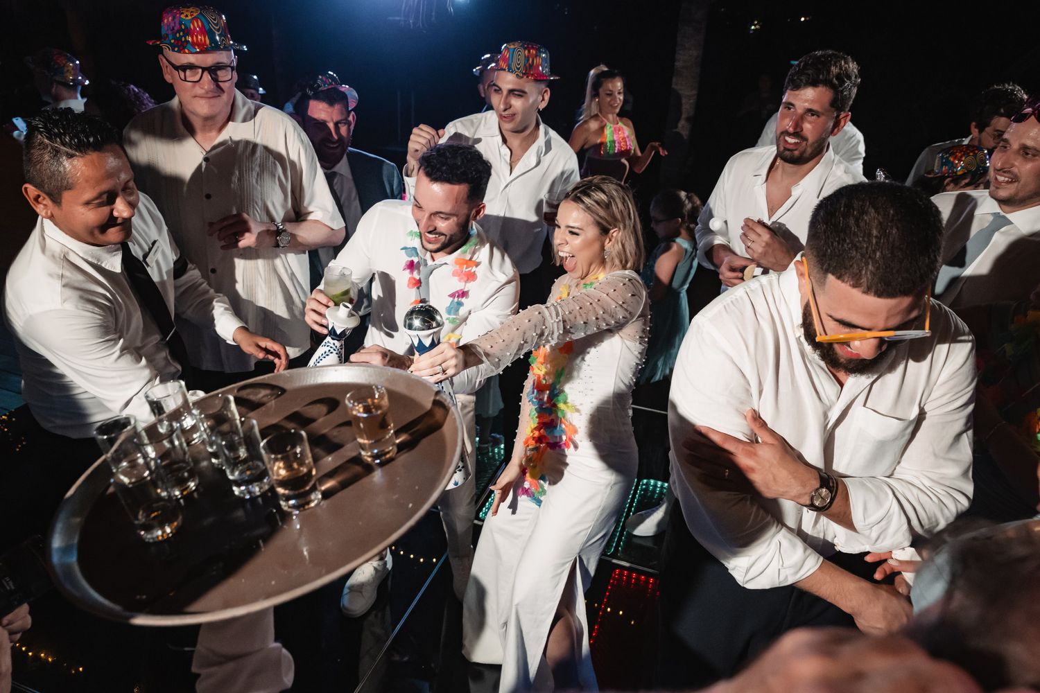 Wedding guests celebrate with bride and groom during lively reception party with colorful leis.