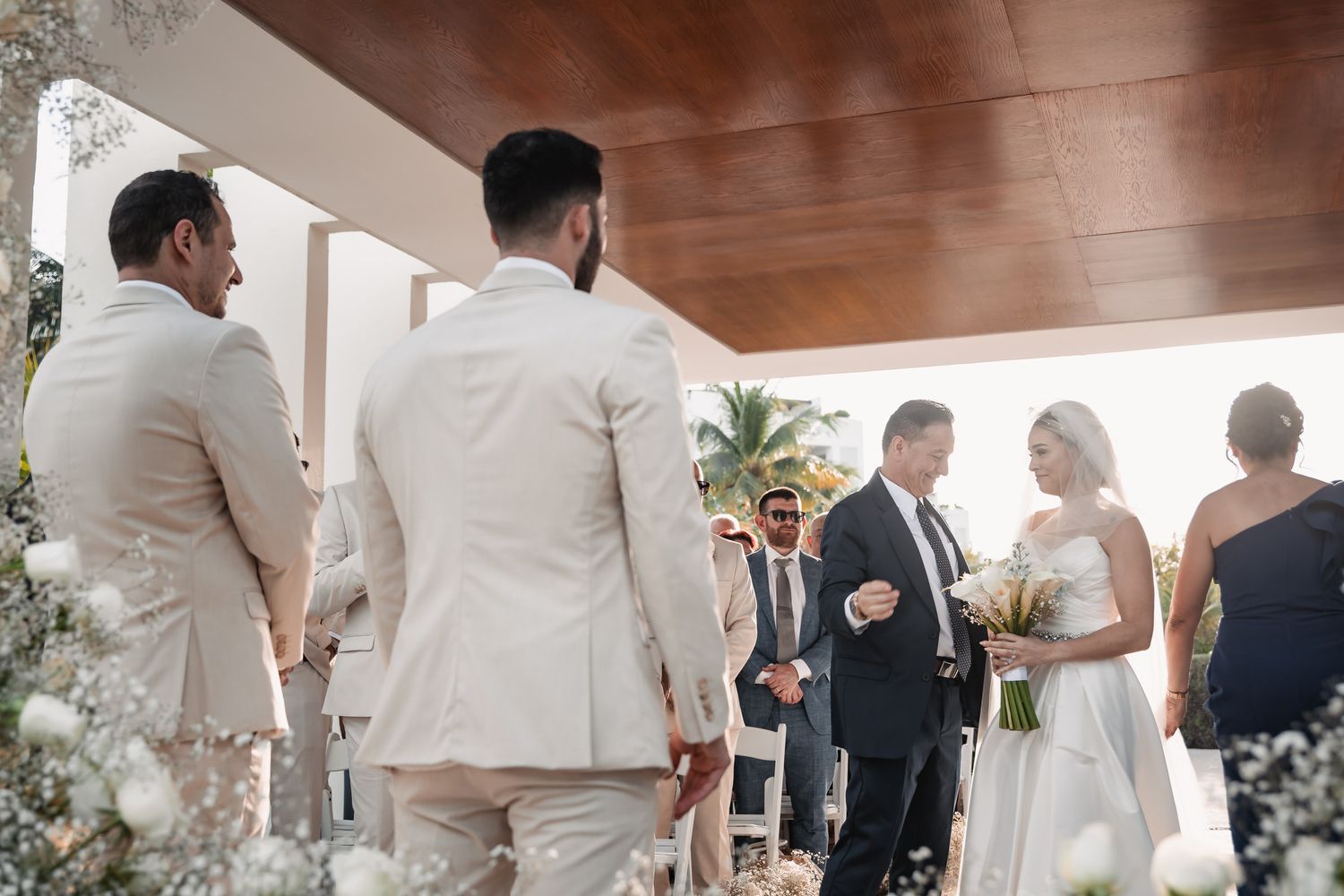 Bride walking down the aisle escorted by her father toward the groom at an elegant outdoor ceremony.