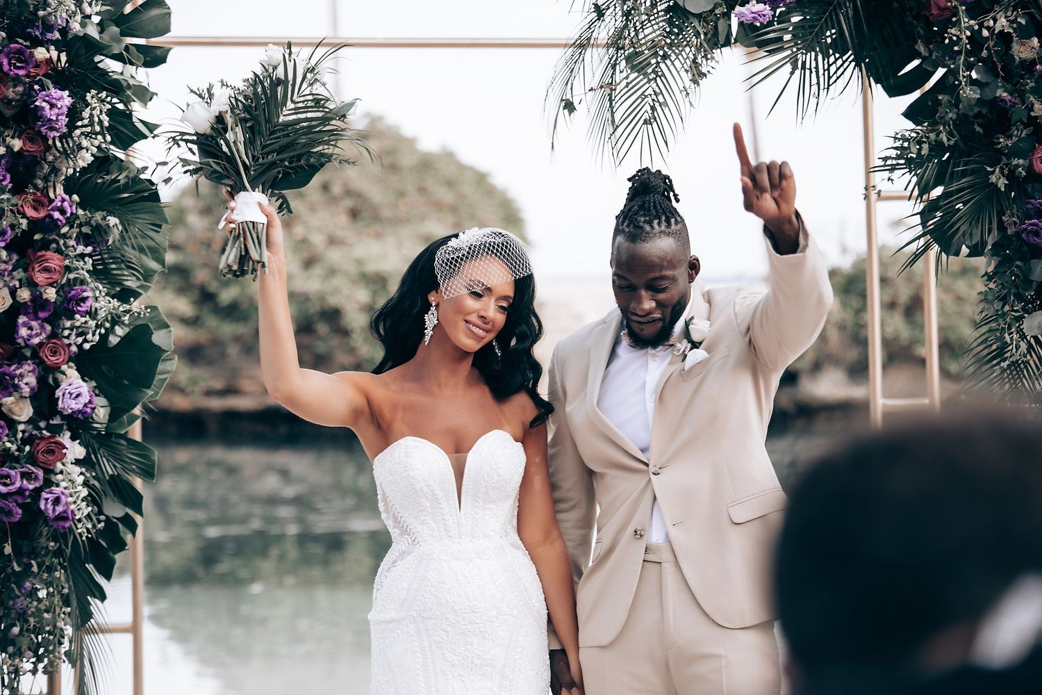 Joyful wedding celebration on a tropical beach with floral decorations.