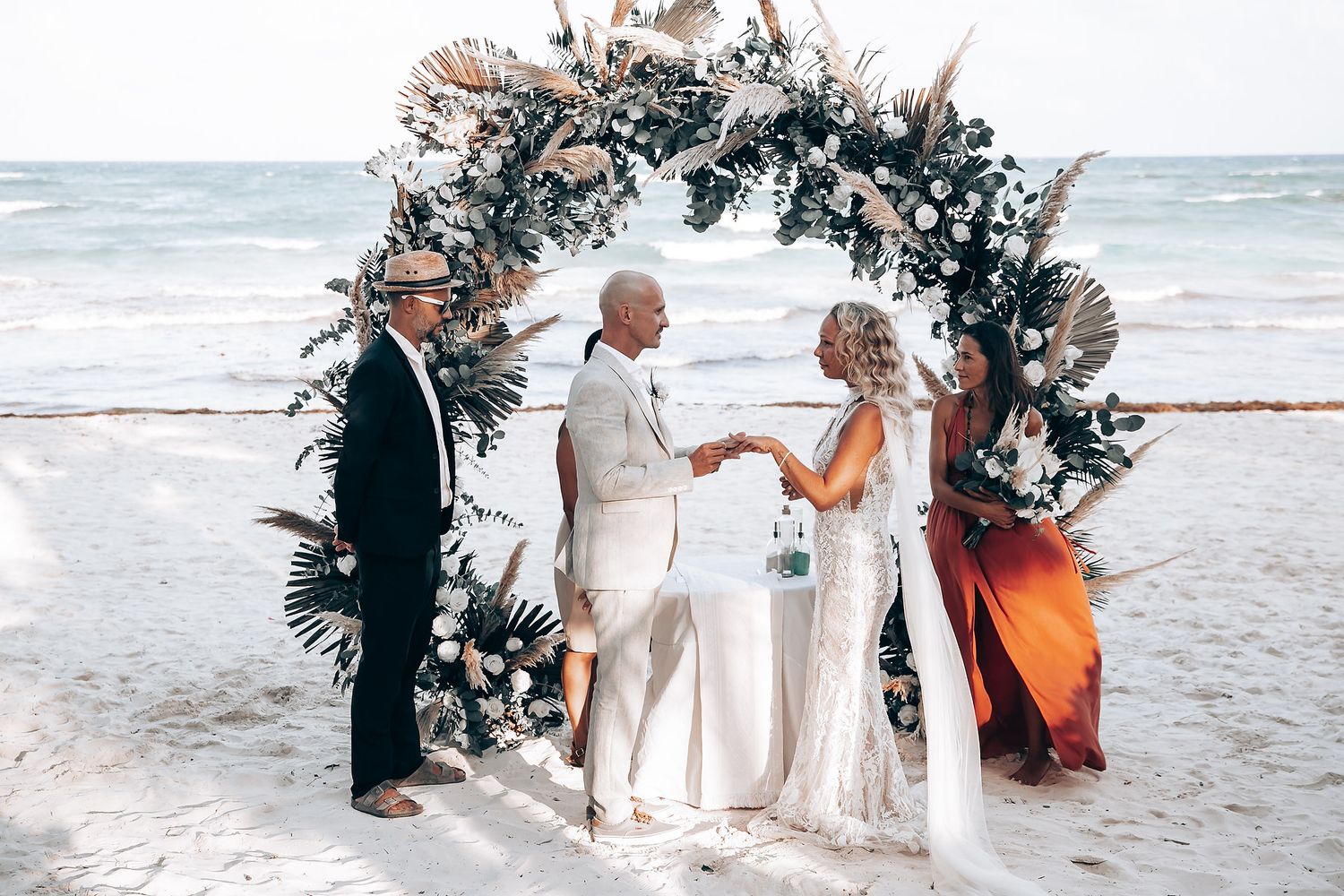 A beautiful beach wedding ceremony with floral arch and ocean backdrop.