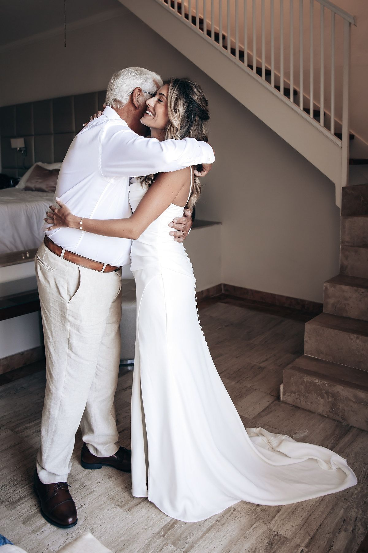 A bride and groom embrace tenderly on a staircase.