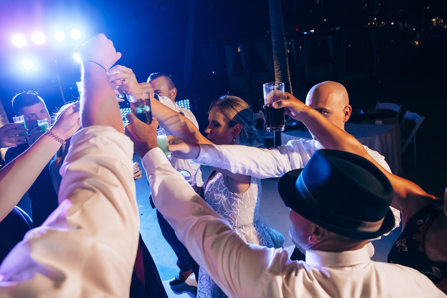 A crowd of people raising their hands and holding smartphones at a concert or event.