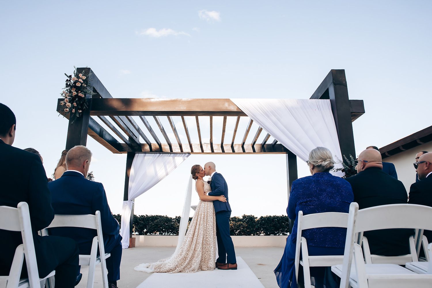 A couple exchanging vows under a decorated arch at their outdoor wedding ceremony.