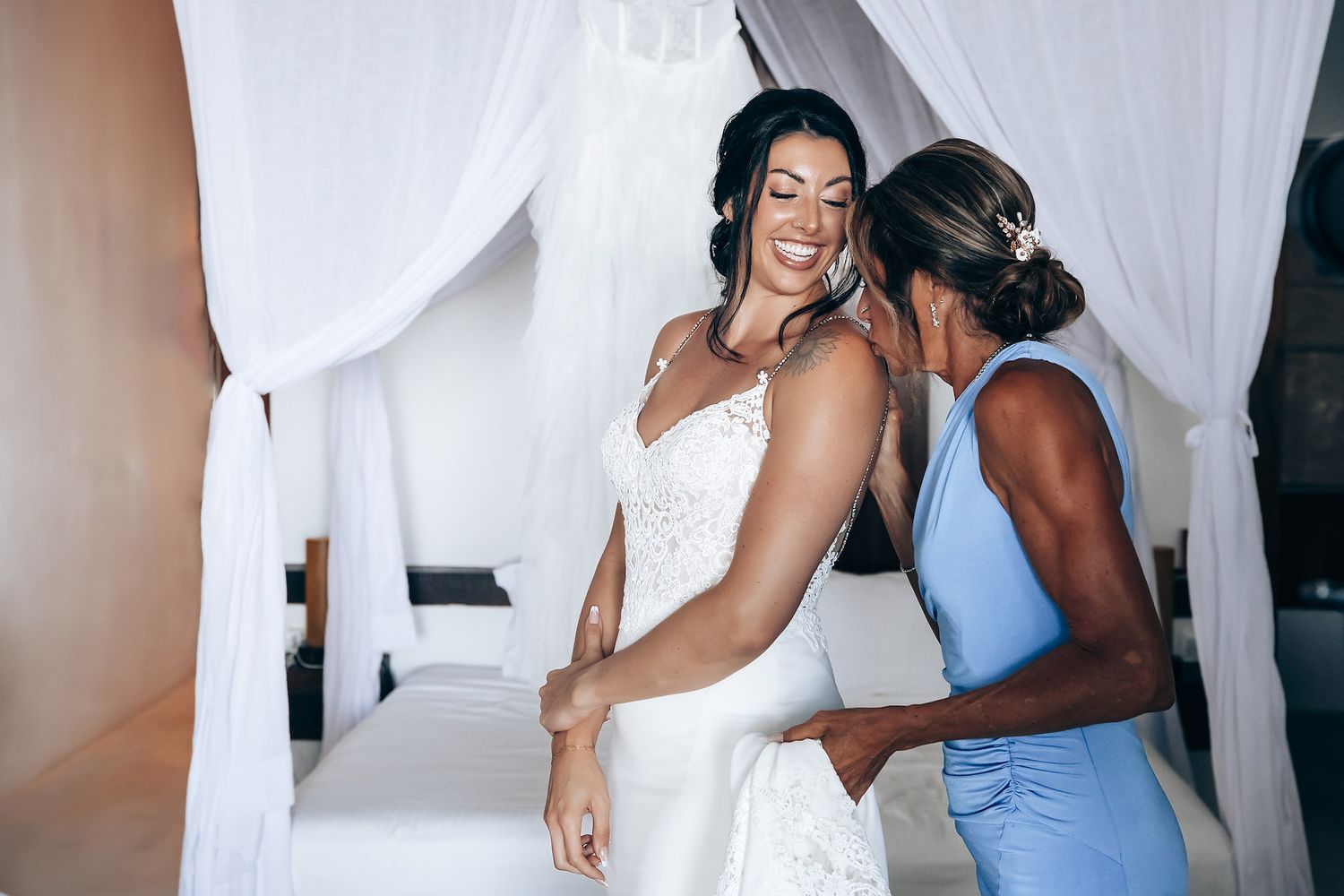Two women in wedding attire standing together and embracing.