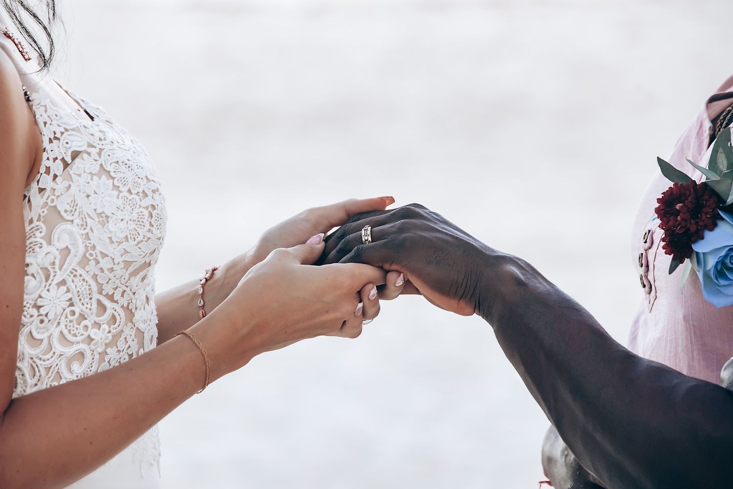 A person's hand applies makeup to another person's face, with flowers in the background.