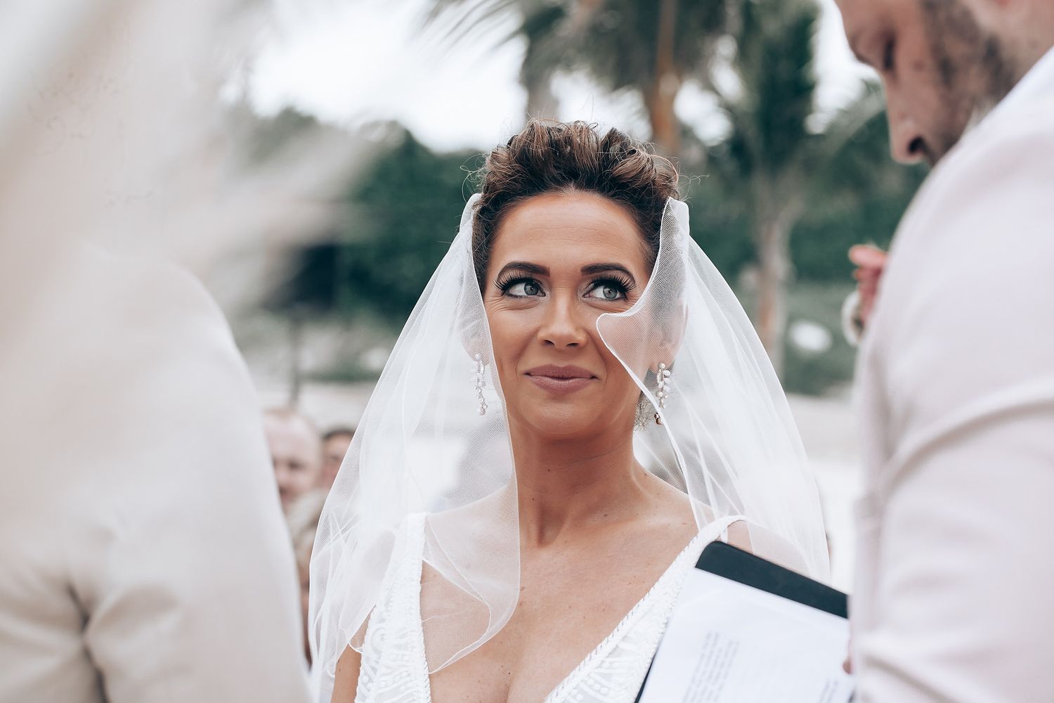 Emotional outdoor wedding ceremony moment with guests looking on.