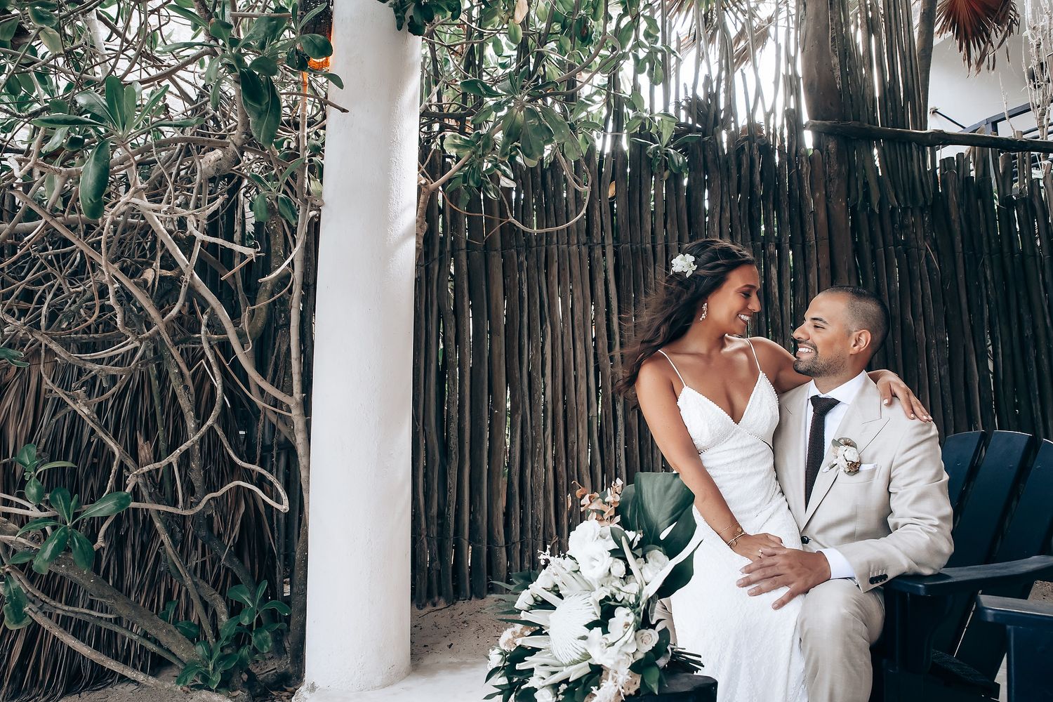 A wedding celebration in an intimate bamboo-walled venue decorated with natural elements and soft lighting.