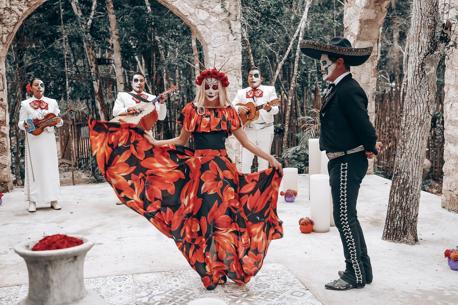 Dancing couple in snow covered forest with red floral dress creating magical winter scene.