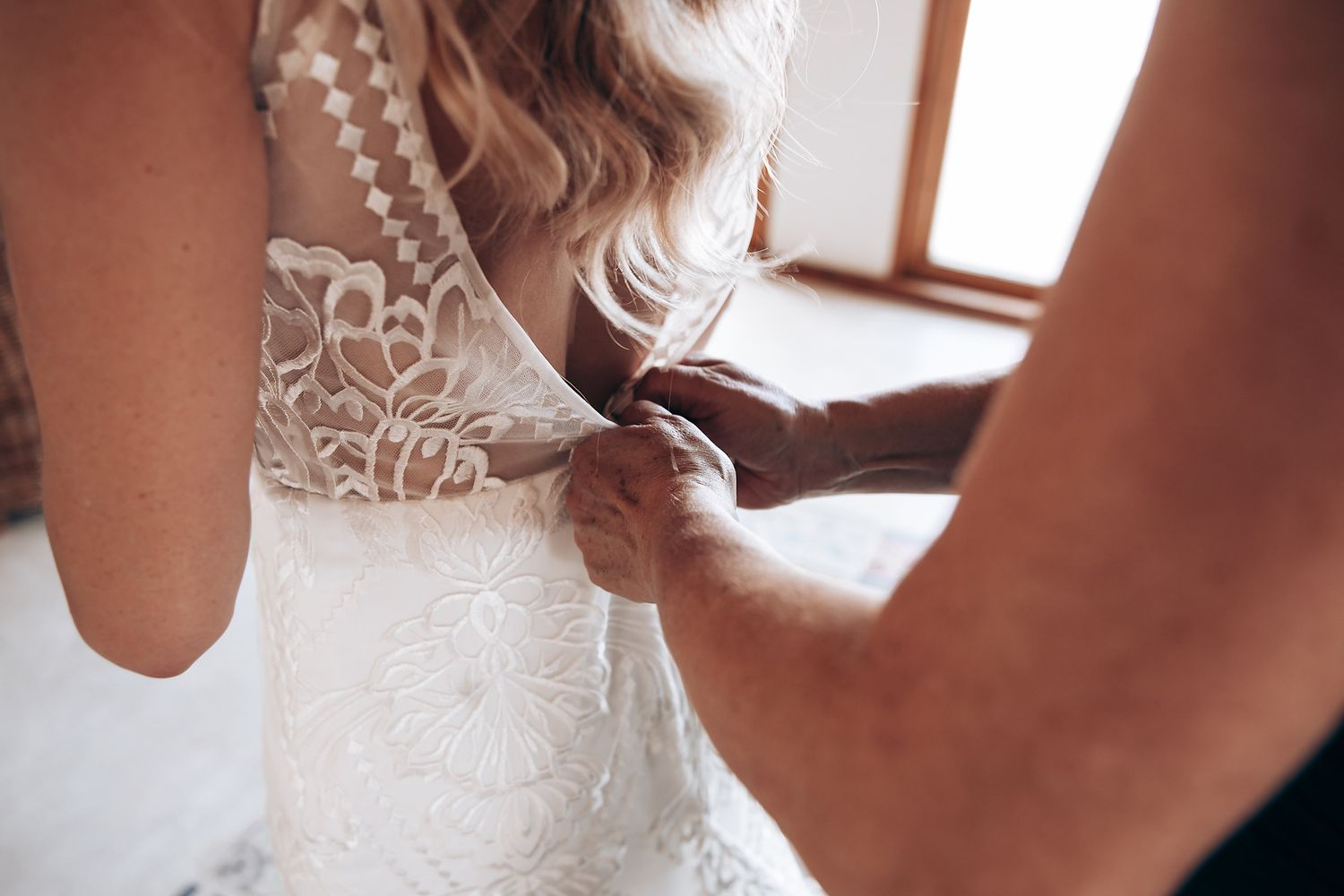 Close-up details of delicate lace and beadwork on a white wedding dress.