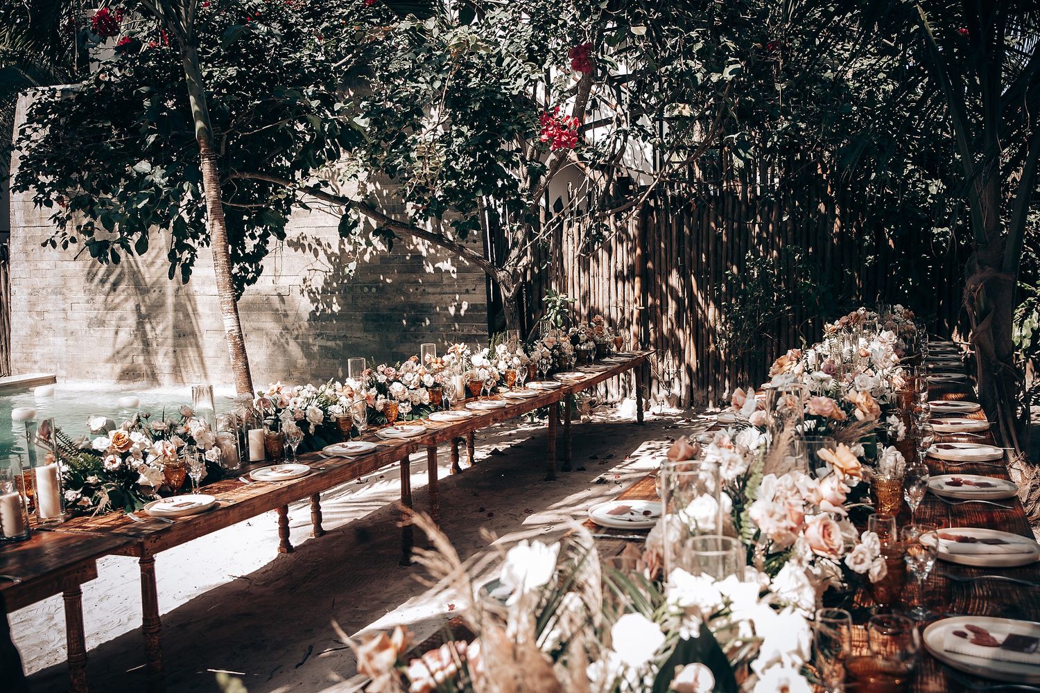Tropical wedding ceremony setup with white chairs and floral decorations along a palm tree-lined path.