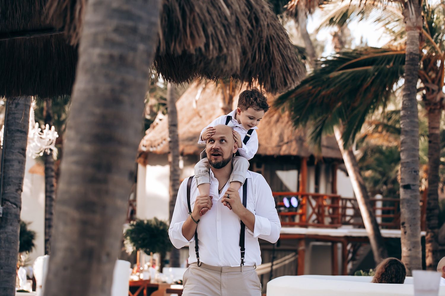 Outdoor wedding ceremony setup with wooden chairs and palm trees creating a tropical ambiance.