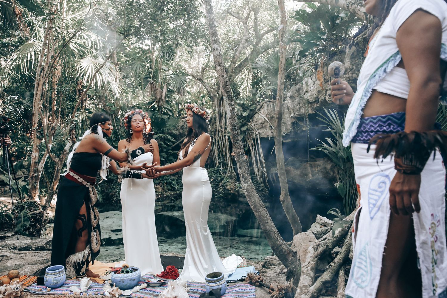 A couple shares a romantic moment during their outdoor wedding ceremony in a wooded natural setting.