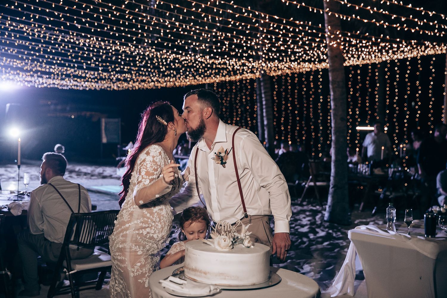 Wedding reception dance floor illuminated by overhead string lights.