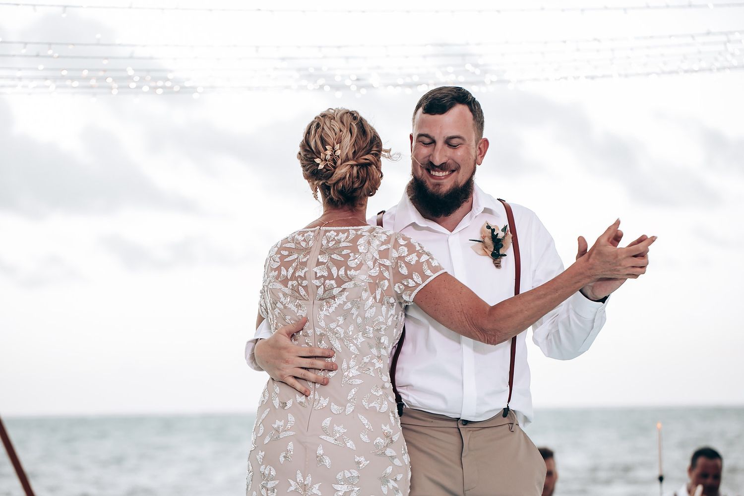 Couple dancing together on beach during their destination wedding celebration.