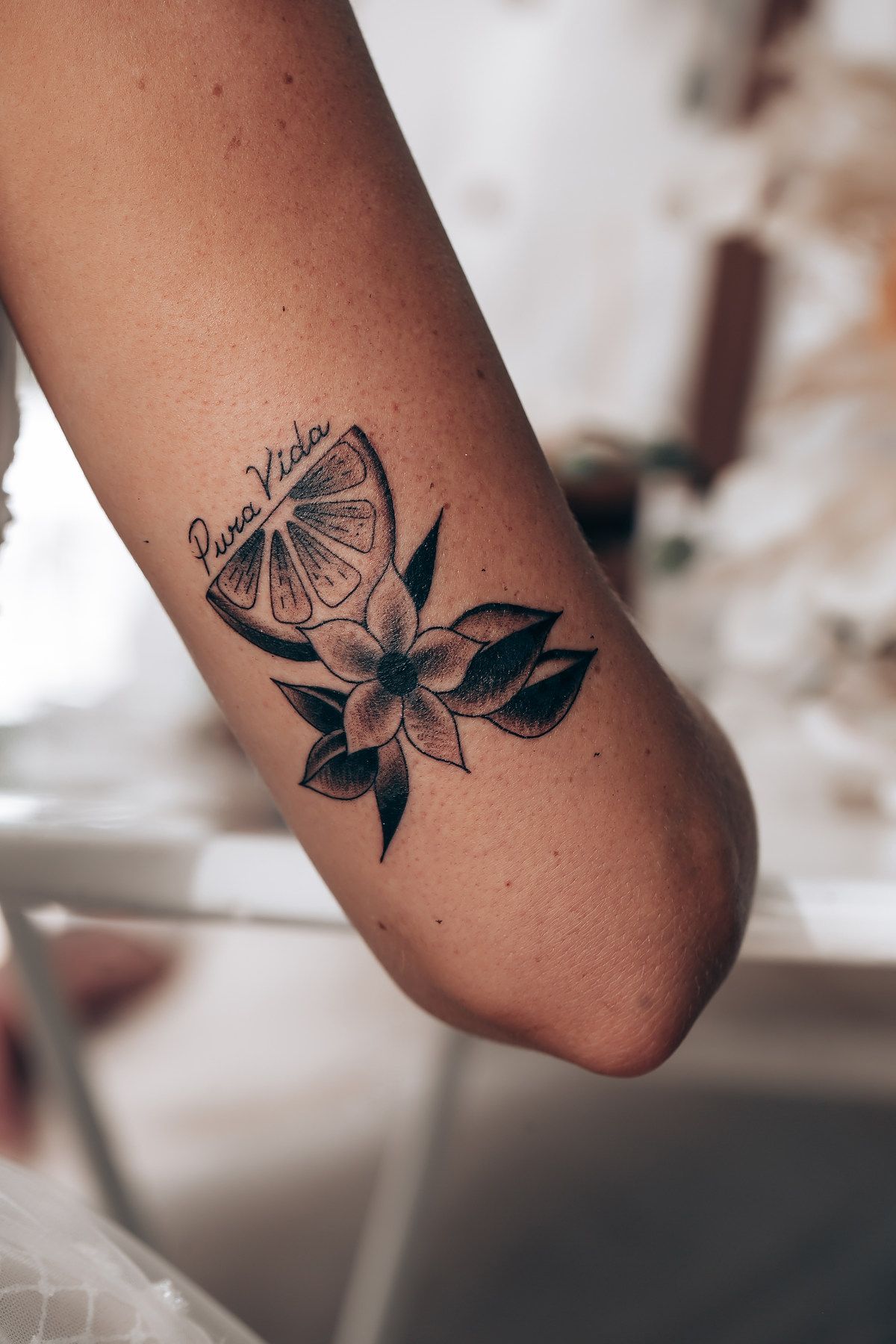 Close-up of a floral tattoo design with black ink on skin showing delicate leaves and petals.