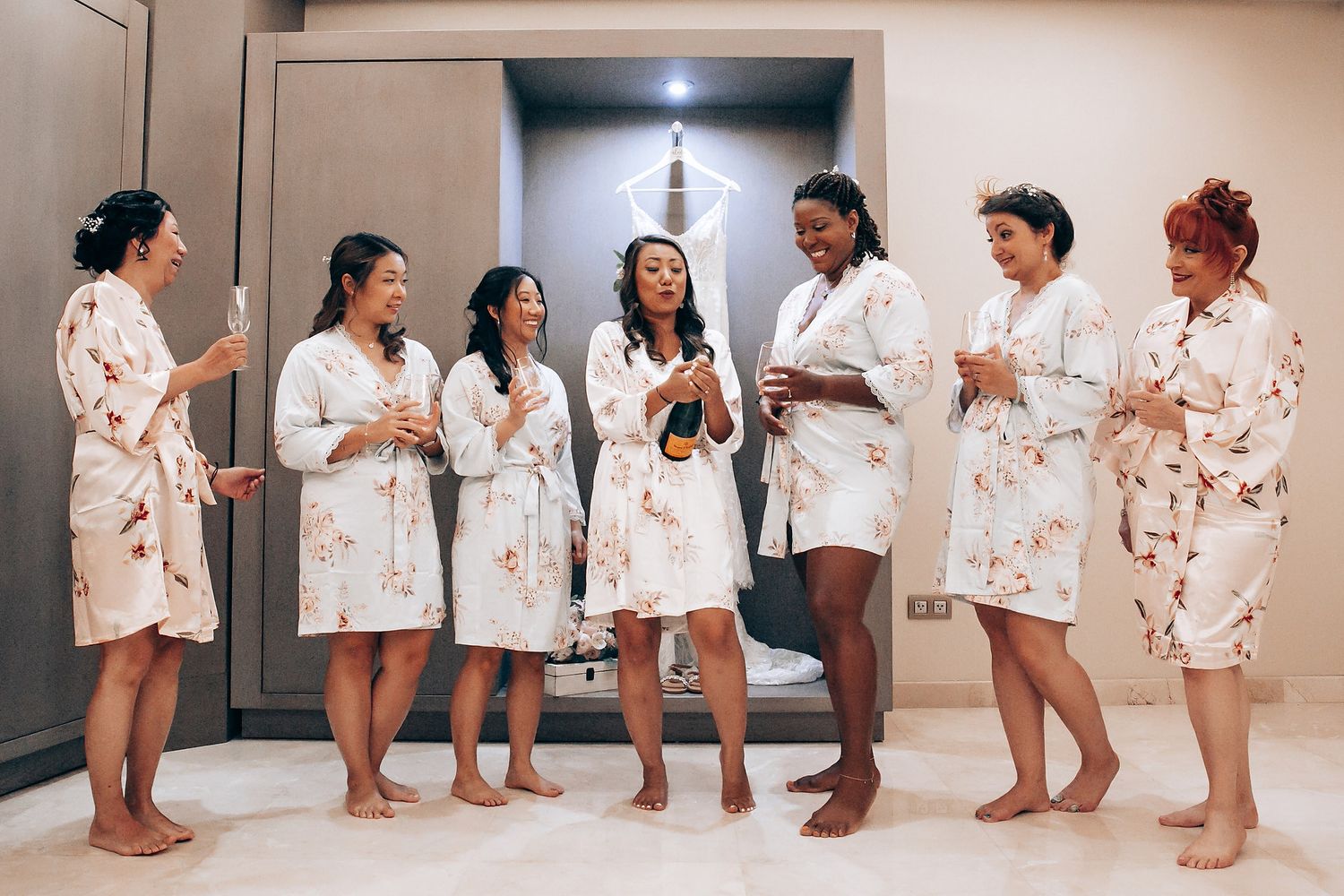 A lineup of people in matching white floral robes standing together in a room.