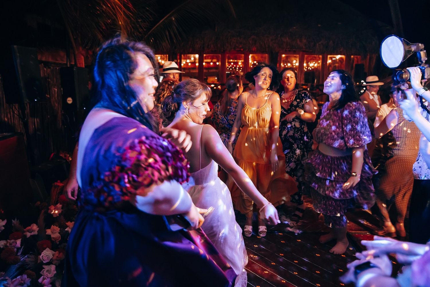 Dance floor at wedding reception with colorful lighting and celebrating guests.