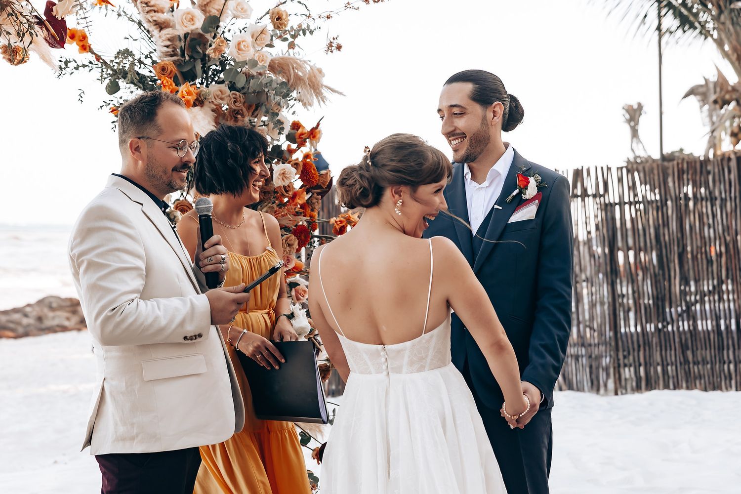 Romantic beachside wedding ceremony with elegant decor and palm trees in the background.