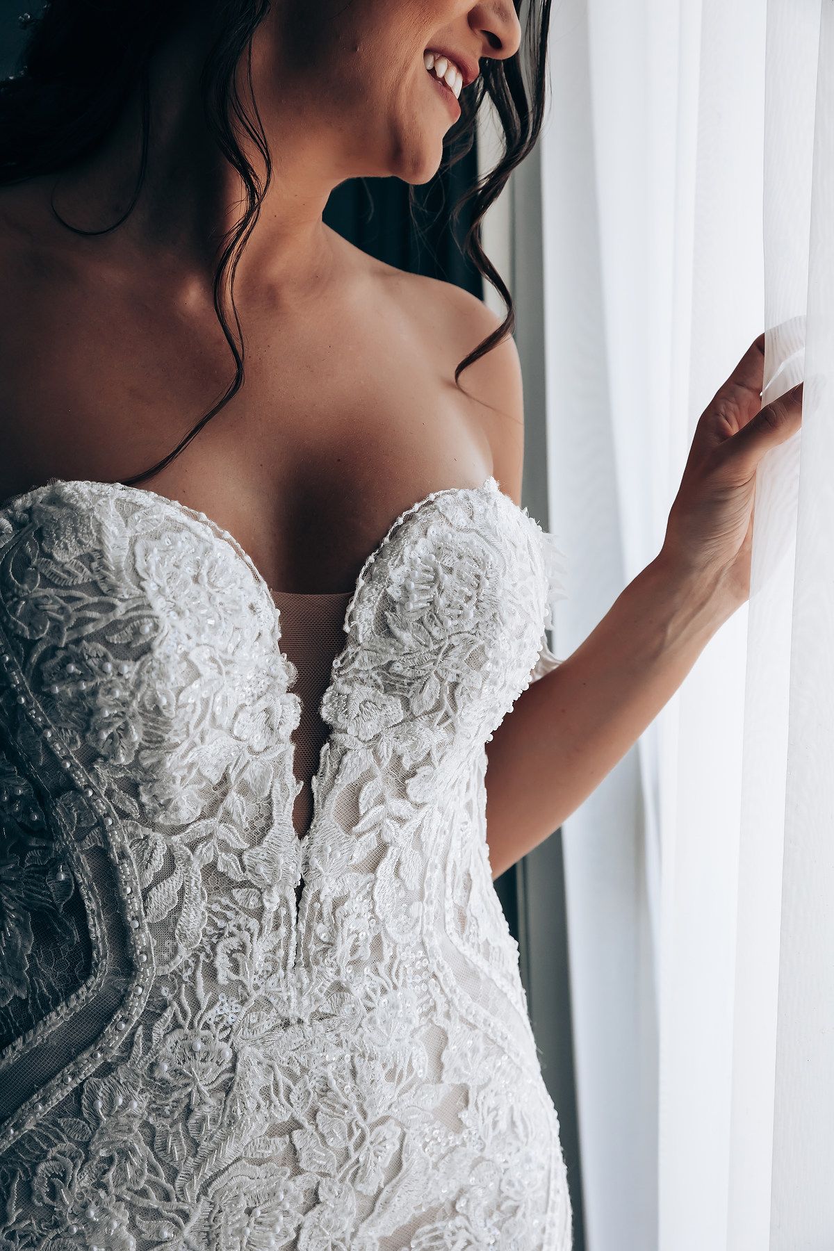 Close-up details of a strapless white lace wedding dress with intricate floral embroidery and plunging sweetheart neckline.
