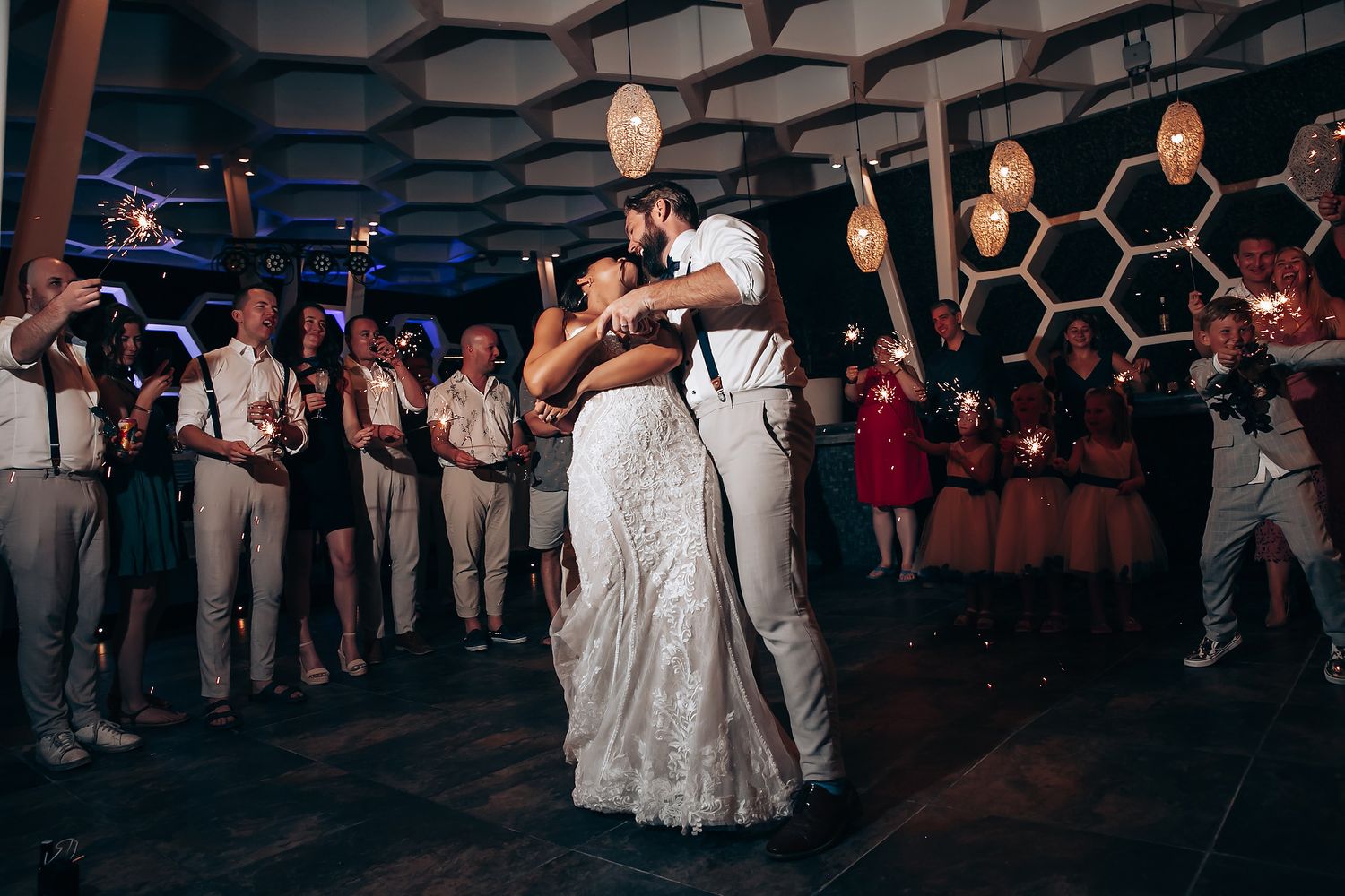 Wedding reception dance floor with hexagonal ceiling design and ambient lighting.