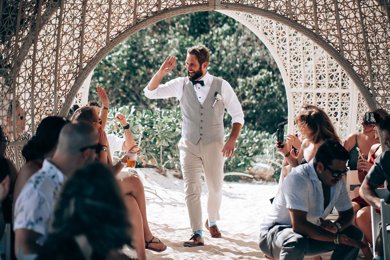 Wedding ceremony taking place under an ornate white lattice archway.