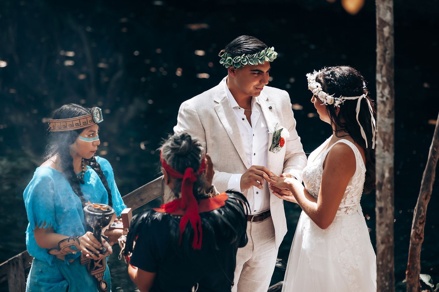 Wedding guests and couple gather in a forest setting with natural rock formations in the background.