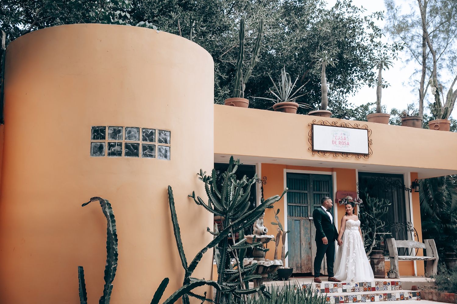 Exterior view of a tropical wedding venue with orange walls and natural landscaping.